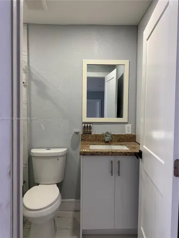 a bathroom with a granite countertop toilet sink and mirror