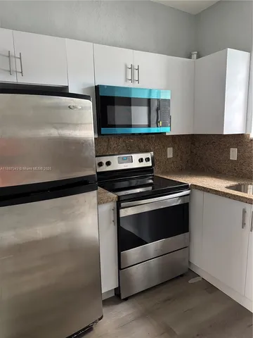 a kitchen with granite countertop a stove and a refrigerator