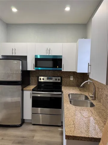 a kitchen with granite countertop a sink stove and refrigerator