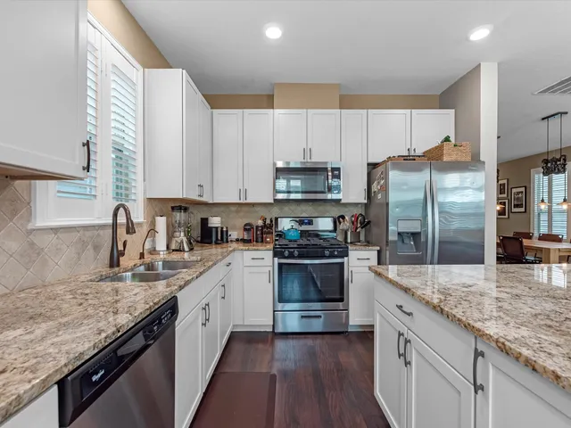 a kitchen with stainless steel appliances granite countertop a sink refrigerator and cabinets