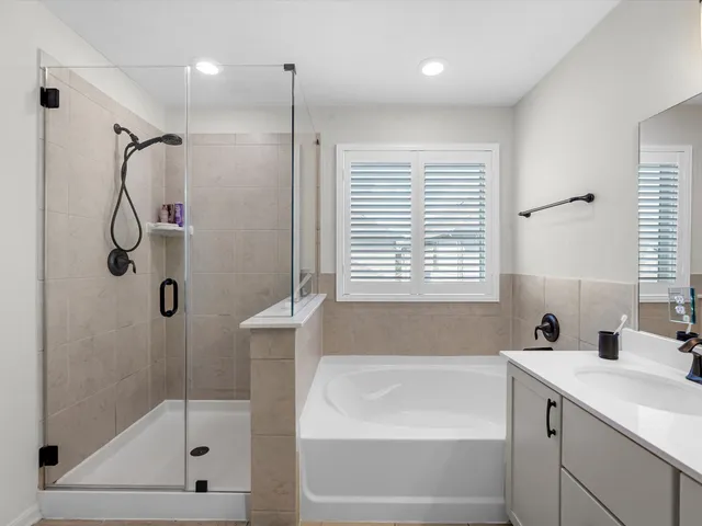 a bathroom with a tub a sink a window and a shower