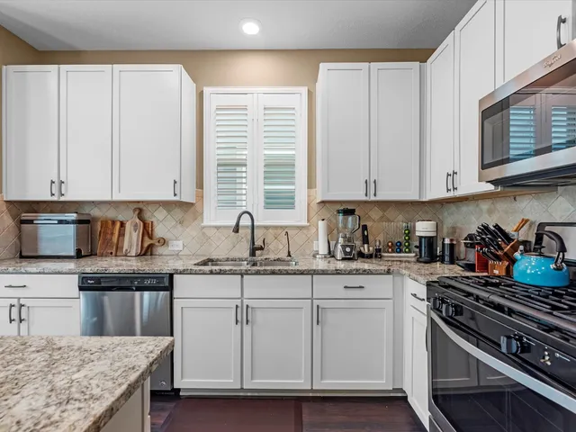 a kitchen with granite countertop a sink stove and cabinets