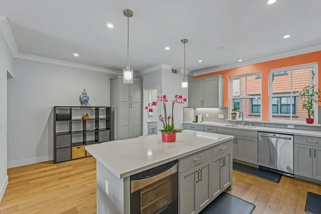 a kitchen with stainless steel appliances kitchen island granite countertop a dining table chairs sink and white cabinets