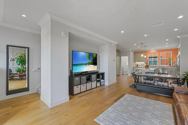 a kitchen with stainless steel appliances granite countertop a refrigerator a oven a dining table and chairs with wooden floor