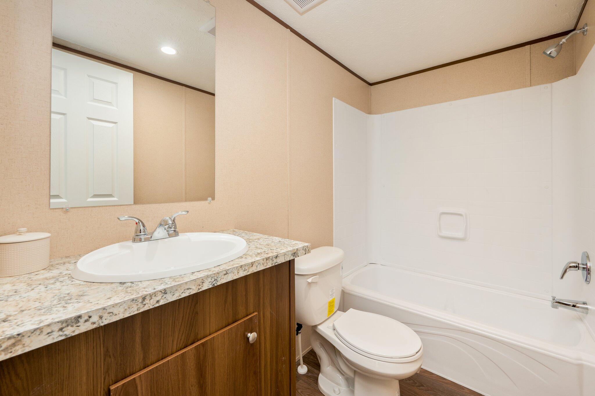 5227 Richardson Road Crestview, FL 32539 - Photo 29 of 44 a bathroom with a granite countertop sink toilet mirror vanity and bathtub