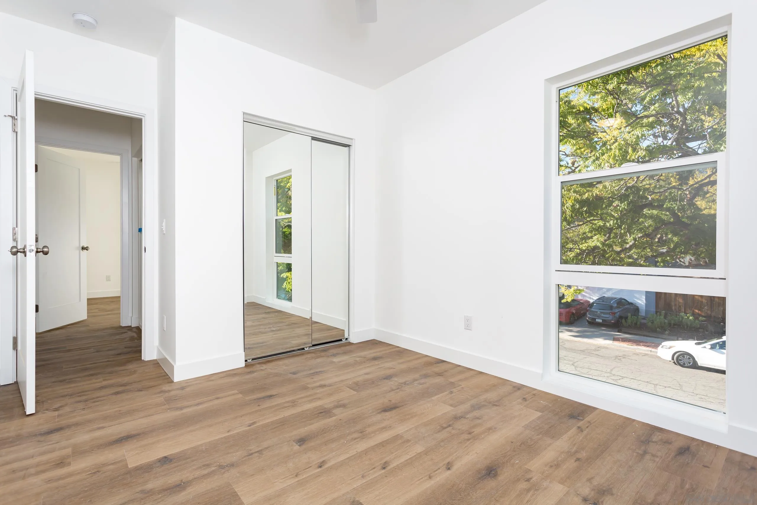 5721-23 Campanile Way San Diego, CA 92115 - Photo 21 of 59 a view of an empty room with wooden floor and a window