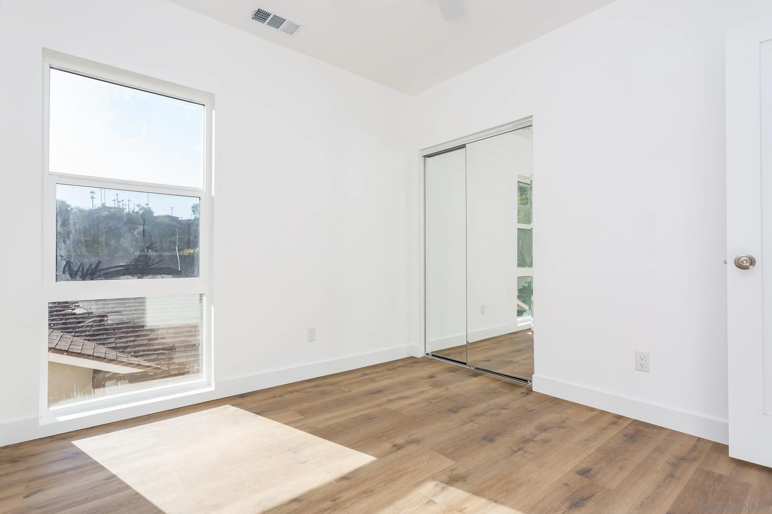 5721-23 Campanile Way San Diego, CA 92115 - Photo 23 of 59 a view of an empty room with wooden floor and a window