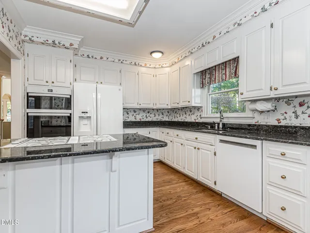 a kitchen with stainless steel appliances granite countertop a sink and cabinets with wooden floor