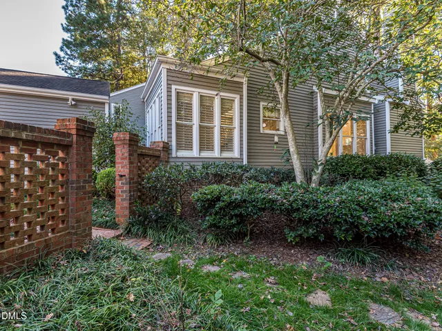 a view of a house with potted plants and a large tree