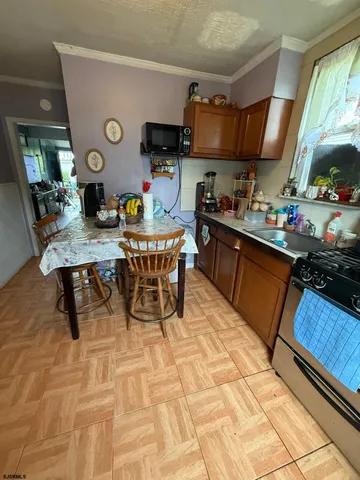 a kitchen with stainless steel appliances granite countertop a sink a stove a dining table and chairs with wooden floor