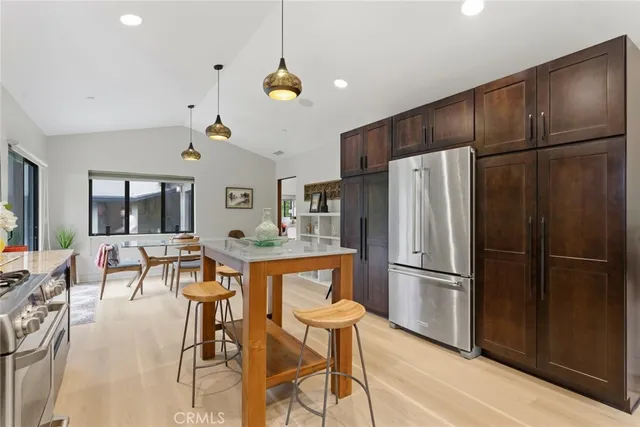 a kitchen with stainless steel appliances a refrigerator a microwave oven a stove and white cabinets with wooden floor