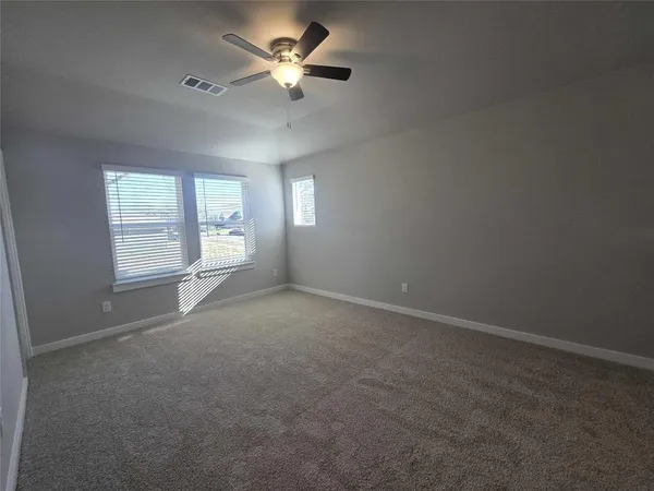 en empty room with windows and ceiling fan