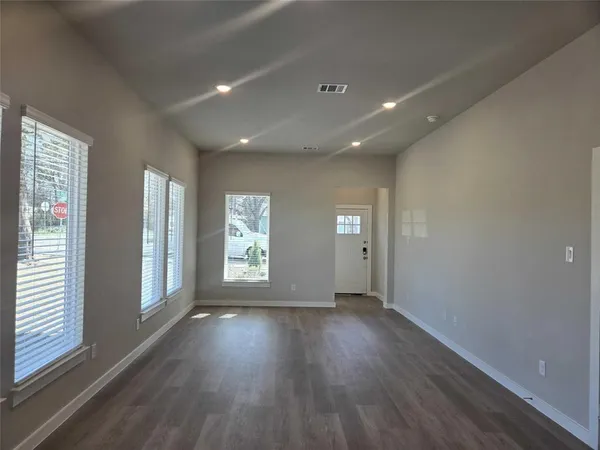 an empty room with wooden floor and windows