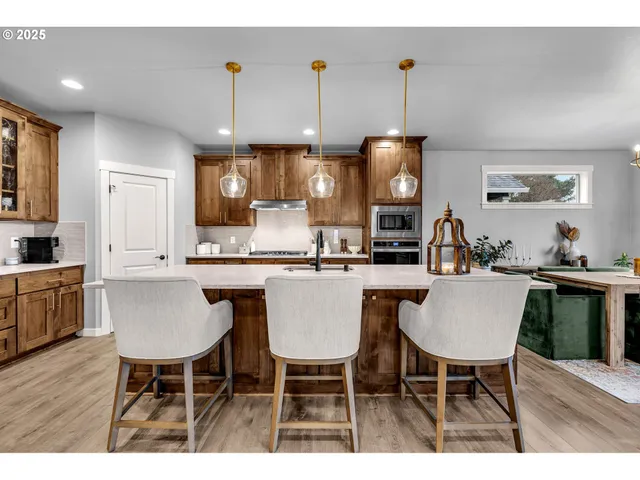 a kitchen with kitchen island granite countertop a table chairs a sink dishwasher a dining table and chairs with wooden floor