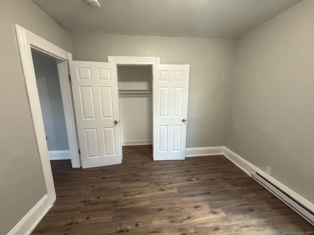 an empty room with wooden floor and closet area