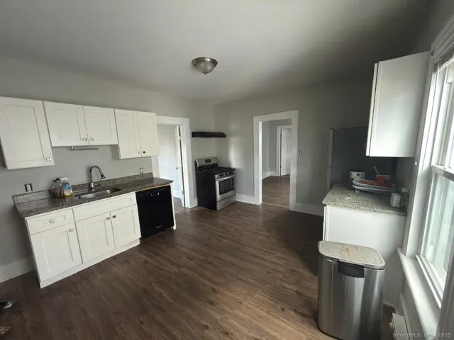 a kitchen with granite countertop a refrigerator stove top oven and sink