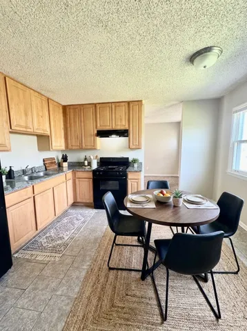 a open kitchen with granite countertop a sink cabinets and stainless steel appliances