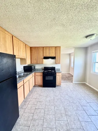 a kitchen with granite countertop a refrigerator and a stove top oven