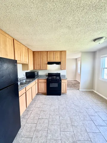 a kitchen with granite countertop a refrigerator and a stove top oven