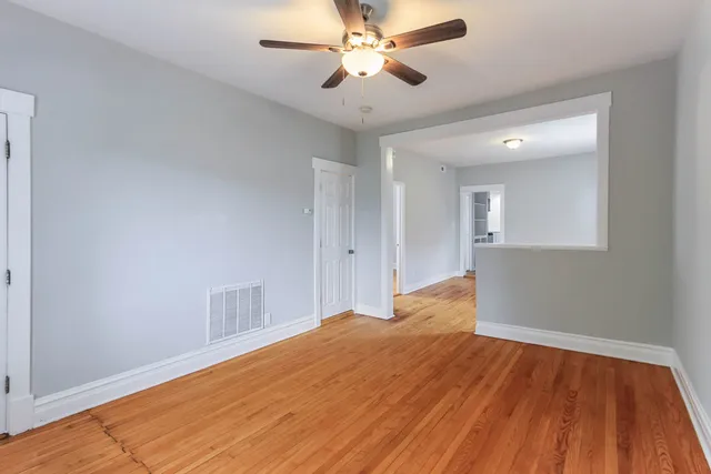 a view of an empty room with a window and wooden floor