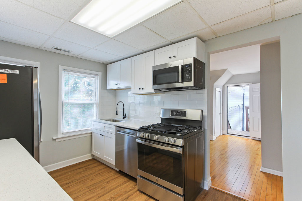 6046 West Giddings Street Chicago, IL 60630 - Photo 33 of 46 a kitchen with stainless steel appliances granite countertop a stove top oven a sink dishwasher a microwave oven and a refrigerator with wooden floor