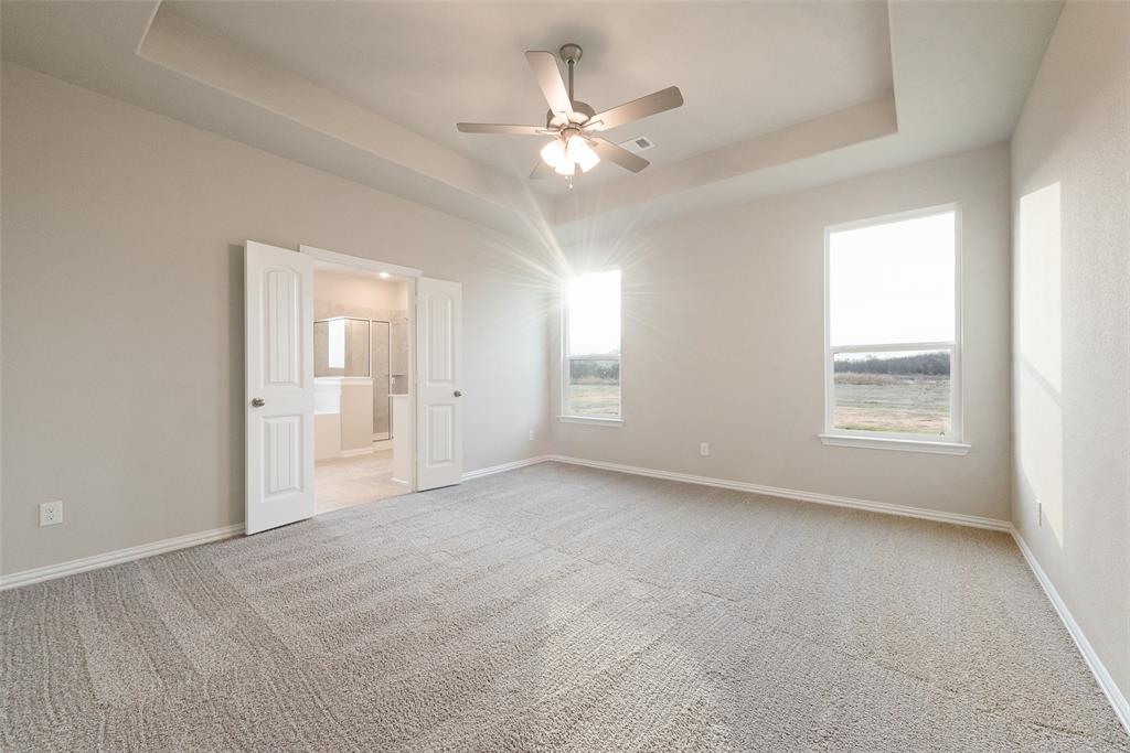 1230 County Road 200 Valley View, TX 76272 - Photo 16 of 26 Unfurnished bedroom with light colored carpet, a raised ceiling, ceiling fan, and ensuite bath