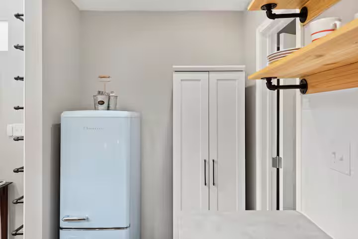 307 East 35th Street, Unit A Austin, TX 78705 - Photo 38 of 40 A compact kitchen area features a retro-style refrigerator and ample storage with open shelving.