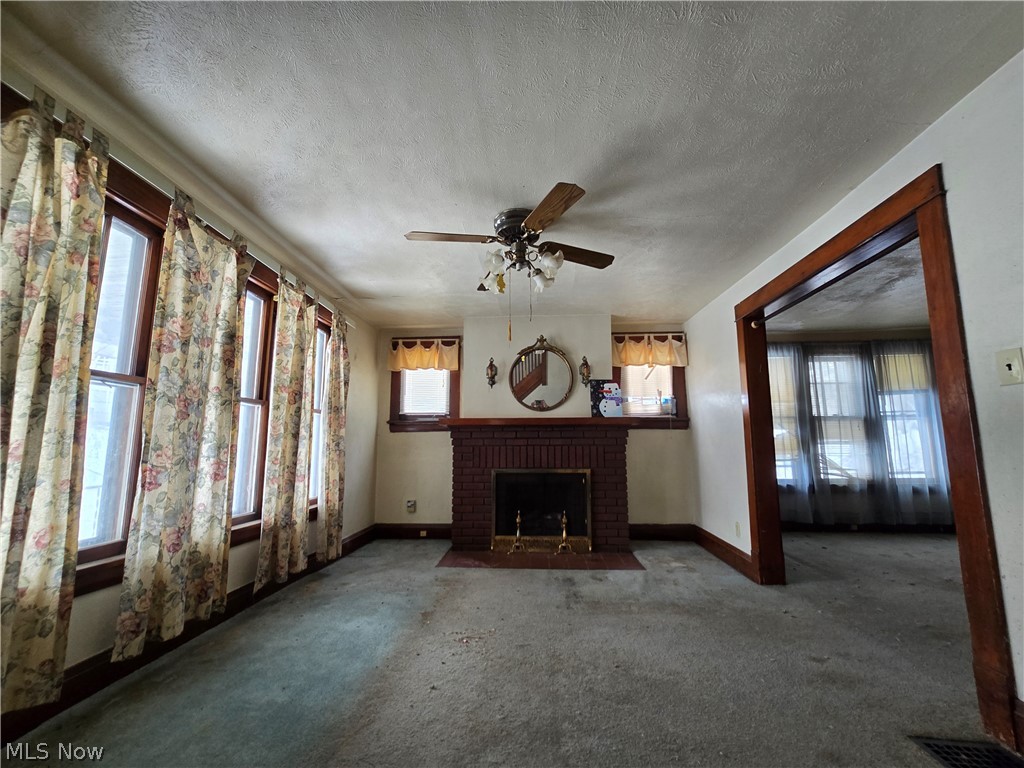 844 National Road Bridgeport, OH 43912 - Photo 6 of 15 Unfurnished living room featuring a ceiling fan, carpet flooring, a textured ceiling, and a brick fireplace