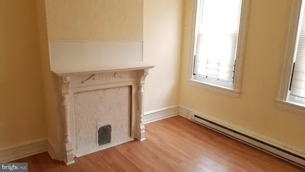 an empty room with wooden floor cabinet and windows