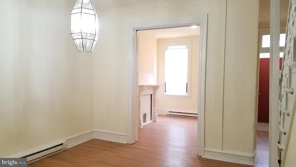 an empty room with wooden floor mirror and windows
