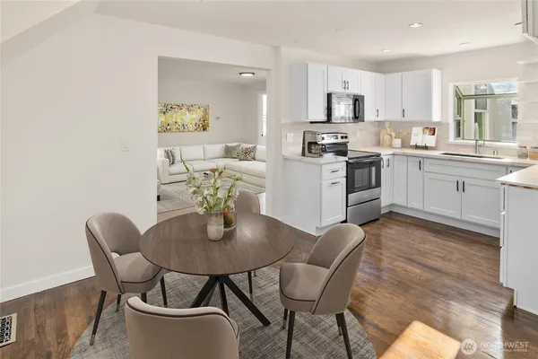 a kitchen with stainless steel appliances granite countertop a dining table chairs and a refrigerator