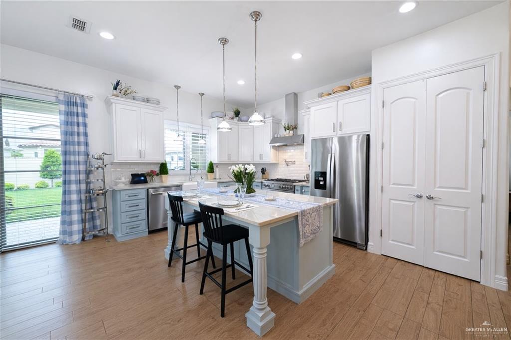 805 Grayson Avenue McAllen, TX 78504 - Photo 7 of 31 a kitchen with stainless steel appliances a refrigerator a stove a sink dishwasher and a dining table with wooden floor
