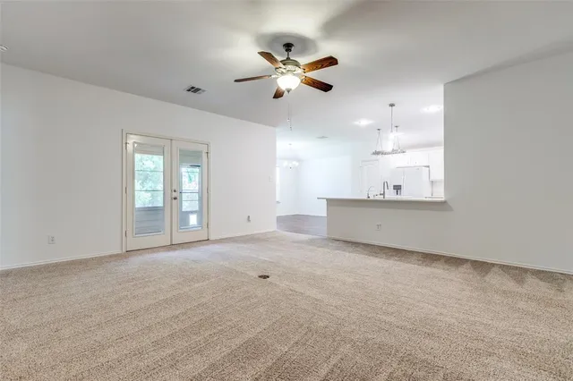 a view of an empty room with a ceiling fan and window