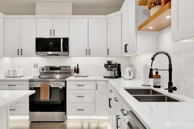 a kitchen with stainless steel appliances granite countertop a stove a sink and a white cabinets