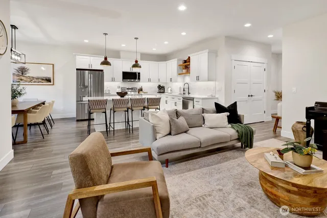 a living room with furniture kitchen area and a wooden floor