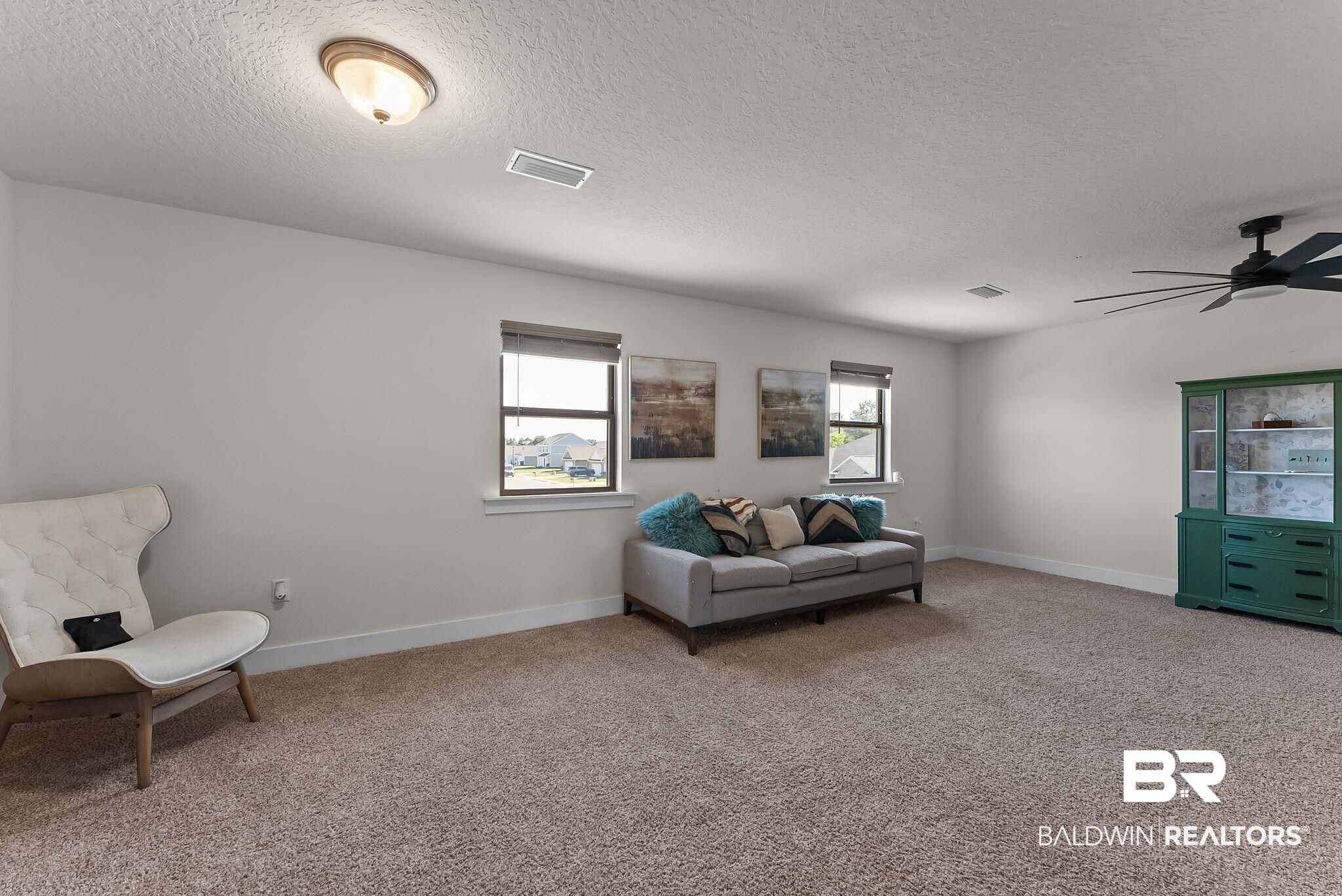16607 Prado Loop Loxley, AL 36551 - Photo 18 of 46 Spacious room featuring neutral carpeting, multiple windows with roller shades, and a ceiling fan with integrated lighting