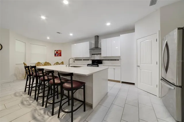 a kitchen with stainless steel appliances kitchen island granite countertop a table chairs sink and cabinets