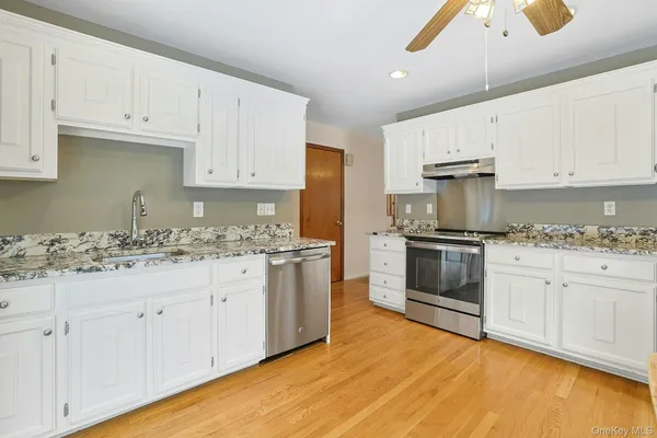 a kitchen with stainless steel appliances granite countertop a dining table chairs refrigerator and sink