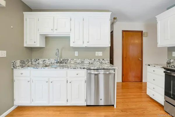 a kitchen with granite countertop white cabinets and white appliances
