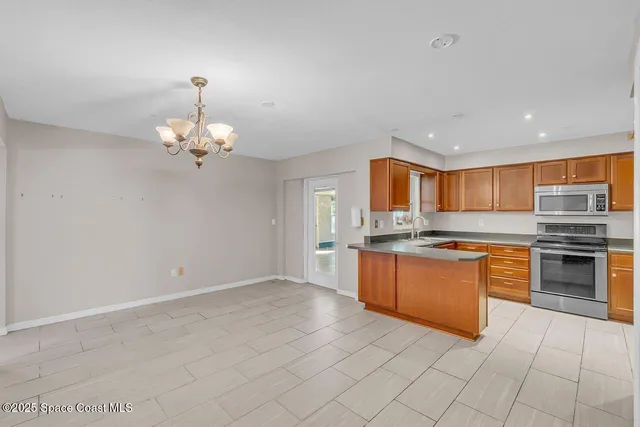 an empty room with chandelier fan and windows