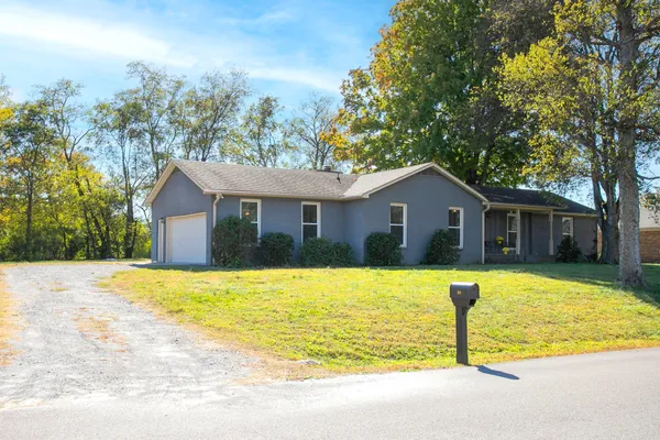 a front view of house with yard and trees in the background