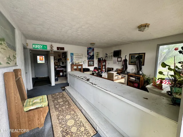 a living room with stainless steel appliances furniture a rug kitchen view and a fireplace