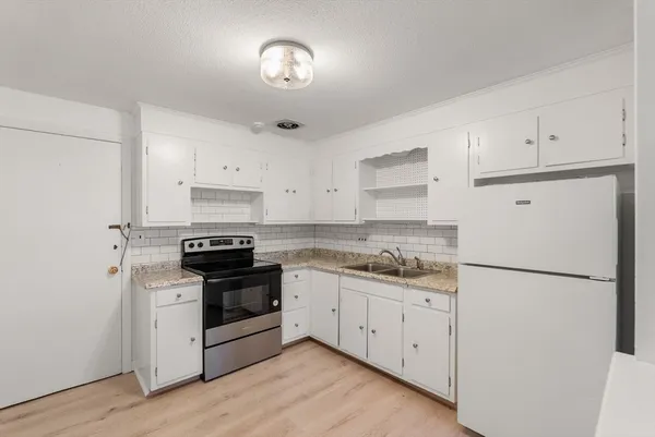 a kitchen with stainless steel appliances granite countertop white cabinets and wooden floor