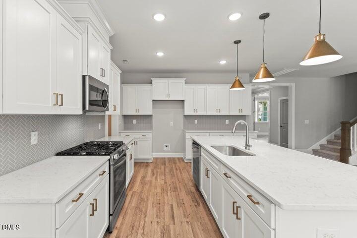 25 West Victoria Rdg Drive, Unit 15 Selma, NC 27576 - Photo 9 of 35 a kitchen with kitchen island granite countertop a sink a stove a refrigerator and white cabinets