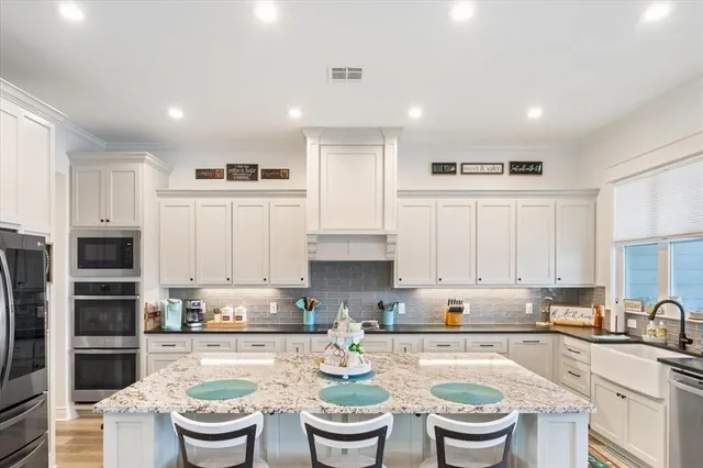 a kitchen with a sink white cabinets and stainless steel appliances