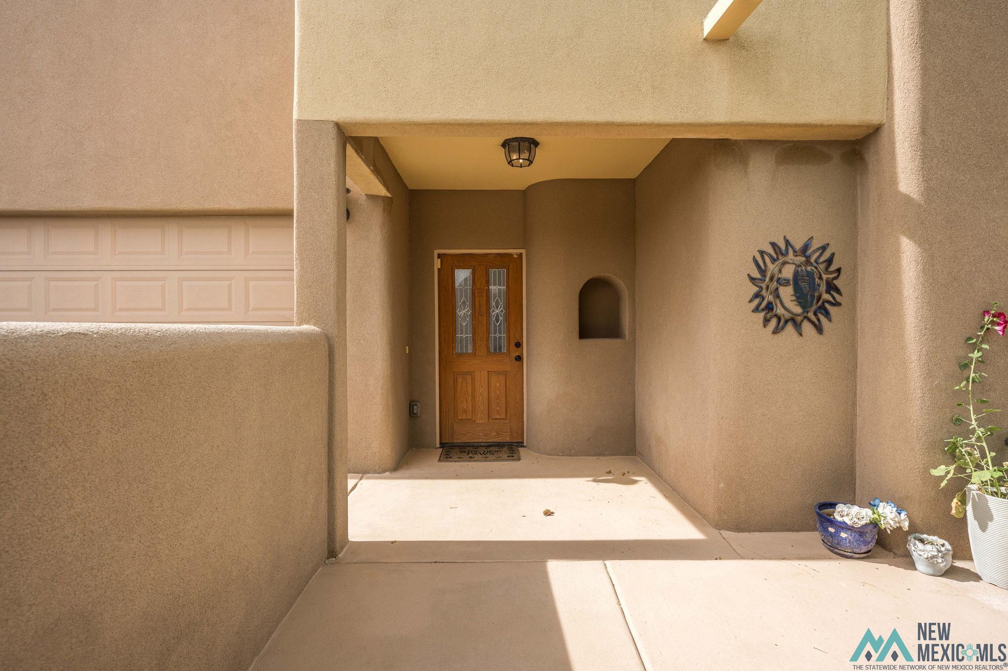 3884 Adriatic Road Las Cruces, NM 88012 - Photo 4 of 45 Stucco exterior featuring a covered entryway with a recessed niche and a paneled front door with decorative glass inserts