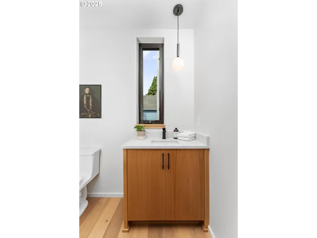 a view of a hallway with wooden floor and a bathroom