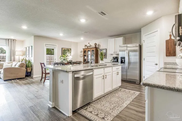 a kitchen with stainless steel appliances granite countertop a refrigerator a stove and a sink