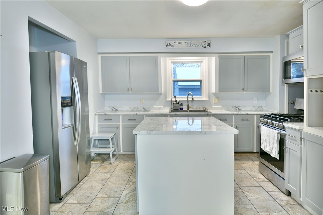 4335 Crew Hood Road Girard, OH 44420 - Photo 16 of 50 Kitchen with appliances with stainless steel finishes, light stone counters, sink, gray cabinets, and a kitchen island
