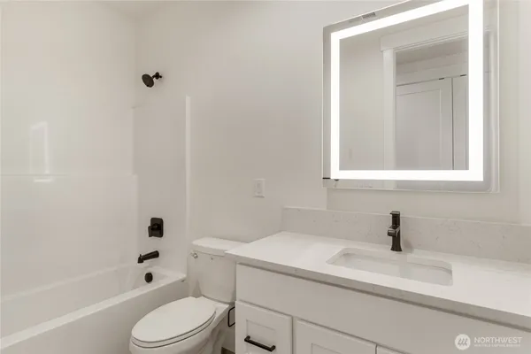 a bathroom with a granite countertop sink and a toilet